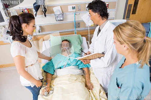 Image of Doctor And Nurse With Woman Looking At Critical Patient