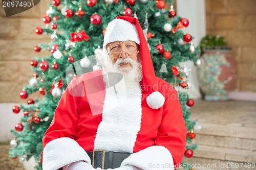 Image of Santa Claus Sitting Against Christmas Tree