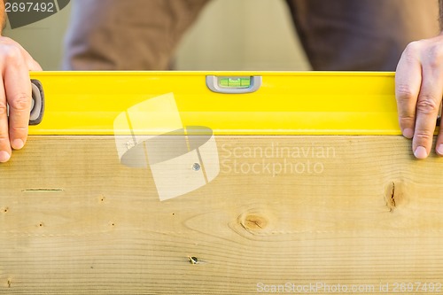 Image of Worker Holding Spirit Level On Wood Outdoors