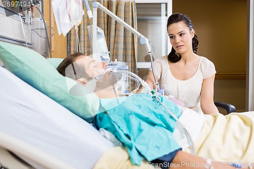 Image of Woman Looking At Critical Patient Lying On Bed