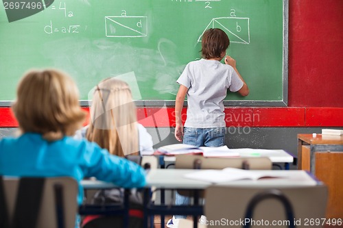 Image of Schoolboy Writing On Greenboard In Classroom