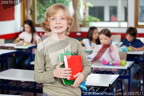 Image of Schoolboy Holding Books With Classmates In Background