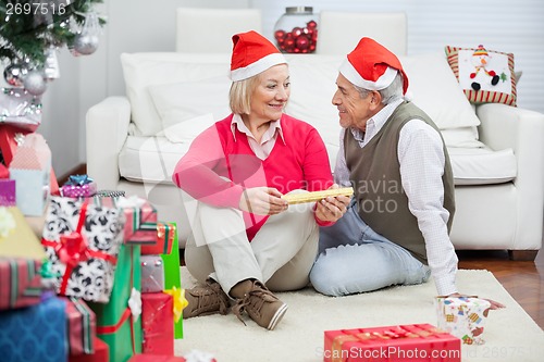 Image of Couple Wearing Santa Hats Looking At Each Other