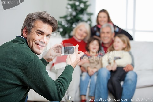 Image of Father Photographing Family Through Mobilephone During Christmas