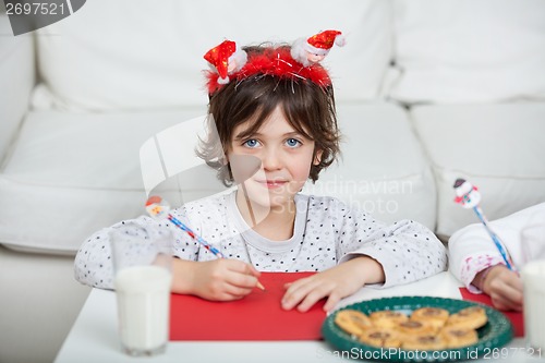 Image of Boy Wearing Santa Headband Writing Letter At Home