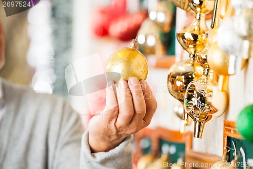 Image of Man Holding Golden Christmas Bauble At Store