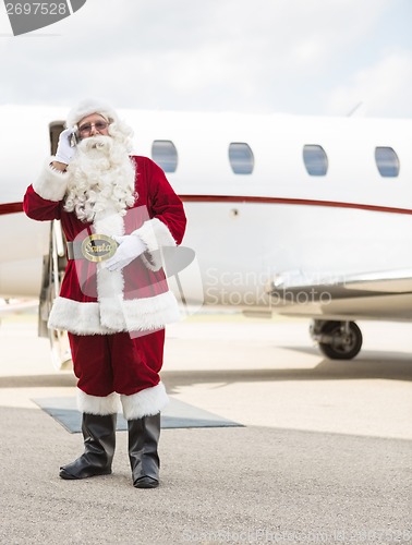 Image of Santa Using Cell Phone Against Private Jet