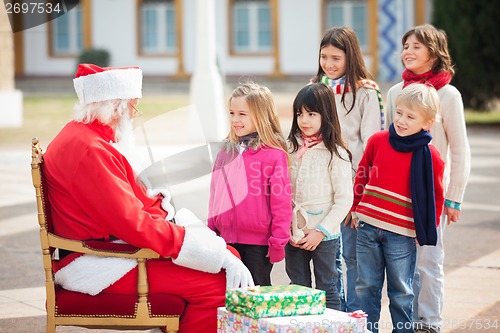 Image of Santa Claus Looking At Children Standing In A Queue