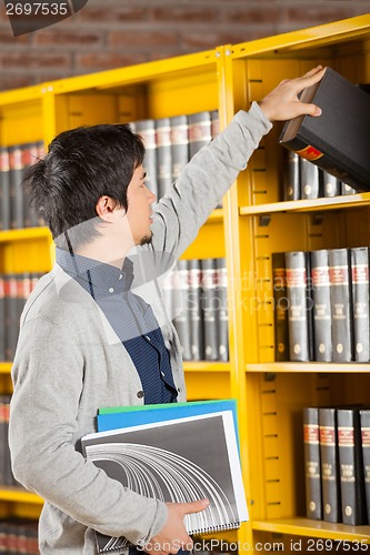 Image of Student Taking Book From Shelf In University Library