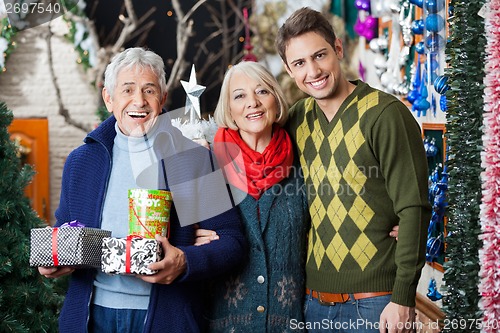 Image of Happy Parents And Son With Presents Standing In Store