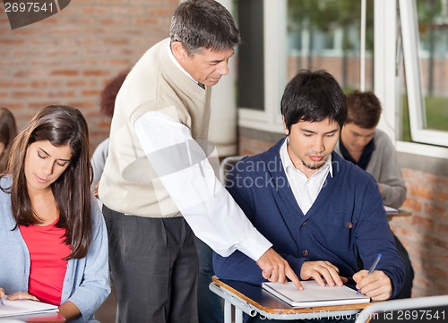 Image of Professor Explaining Test To Student In Classroom