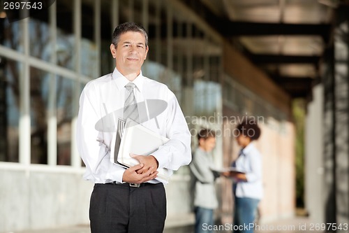 Image of Teacher Holding Books While Standing On Campus