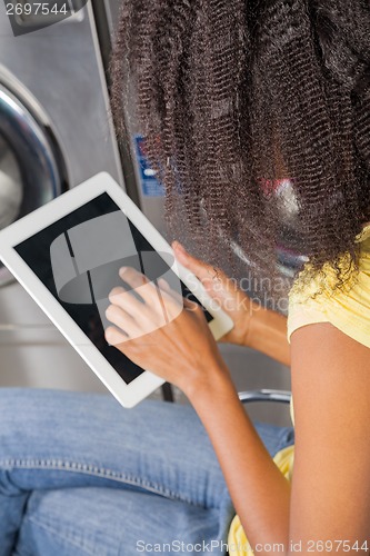 Image of Young Woman Using digital Tablet In Laundry