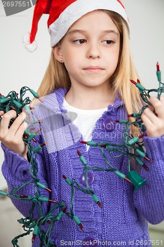 Image of Girl Wearing Santa Hat Looking At Fairy Lights