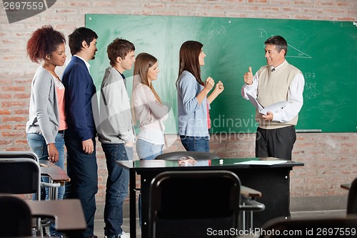 Image of Teacher Gesturing Thumbsup Sign To Successful Student At Classro
