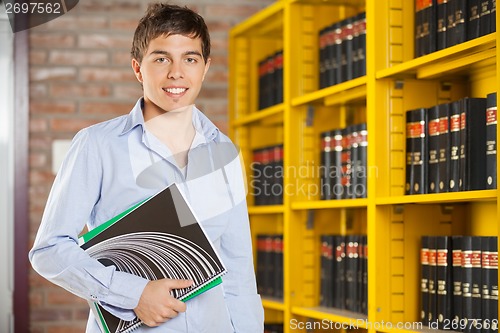 Image of Confident Student Holding Books While Standing In Campus