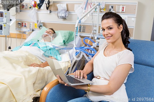 Image of Woman With Laptop Sitting By Male Patient In Hospital