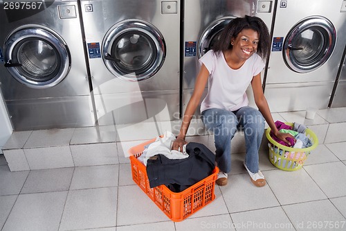 Image of Woman With Baskets Of Dirty Clothes Sitting At Laundromat