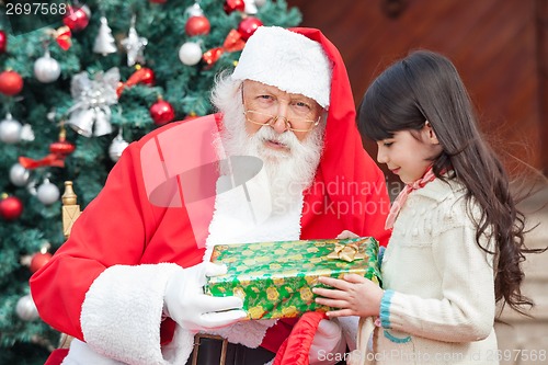 Image of Santa Claus Giving Present To Girl