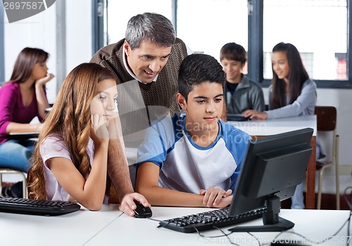 Image of Male Teacher Assisting Students In Computer Class