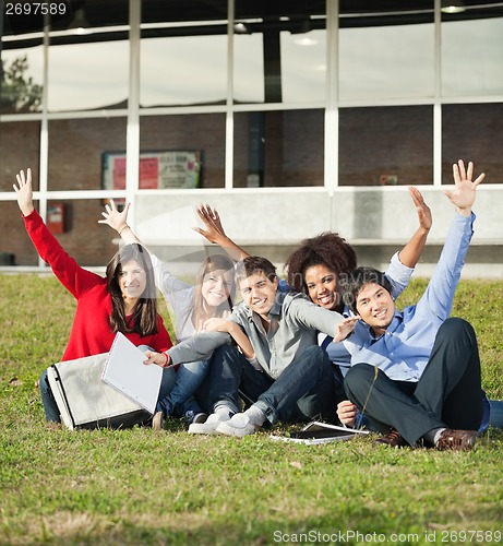 Image of College Students With Hands Raised Sitting At Campus