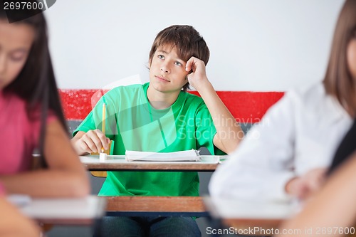 Image of Thoughtful Teenage Schoolboy Sitting At Desk