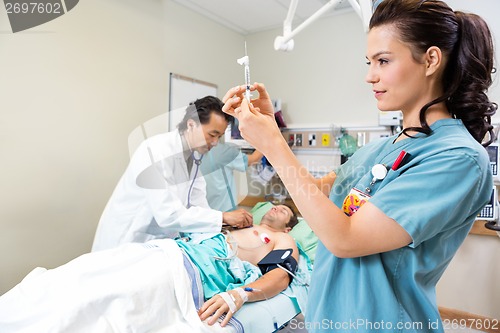 Image of Nurse Preparing Injection While Doctor And Colleague Examining P