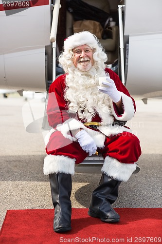 Image of Santa Holding Milk Glass While Sitting On Private Jet's Ladder