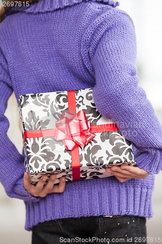 Image of Girl Hiding Christmas Gift Behind Back
