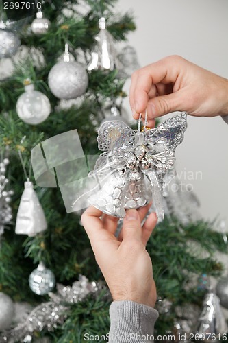 Image of Man Holding Silver Bells In Front Of Christmas Tree