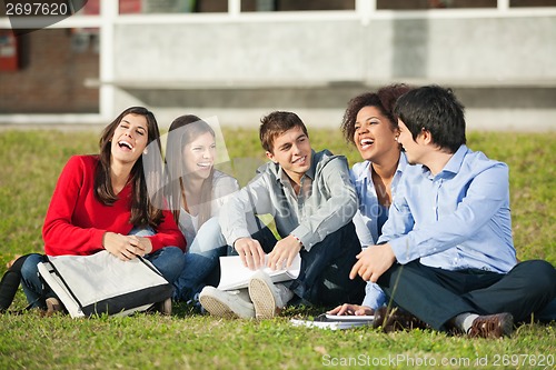 Image of Cheerful College Students Sitting On Grass At Campus