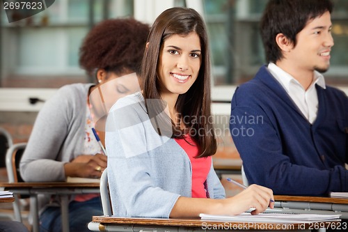 Image of Student Sitting At Desk With Classmates In Classroom