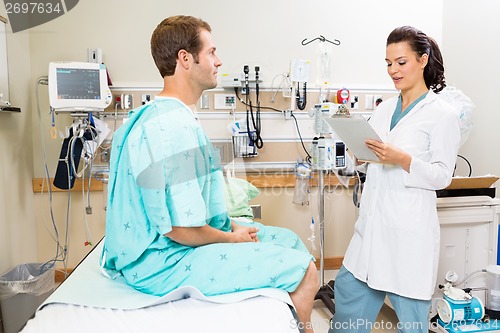 Image of Doctor With Clipboard Discussing Report With Patient