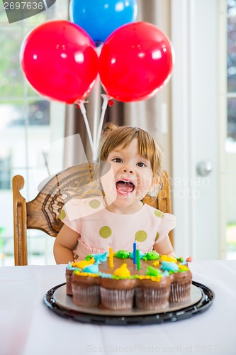 Image of Girl With Mouth Open Sitting In Front Of Cake