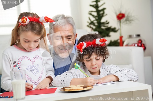 Image of Man Looking At Children Making Christmas Greeting Card