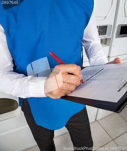 Image of Male Helper Checking List In Laundry