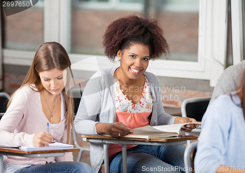 Image of Student With Book Sitting At Desk In Classroom