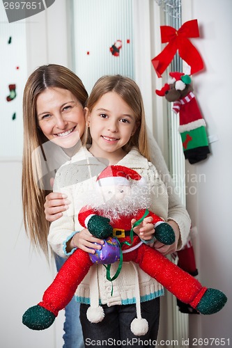 Image of Mother With Daughter Holding Santa Toy At Home