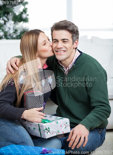 Image of Woman With Christmas Gifts Kissing Man On Cheek