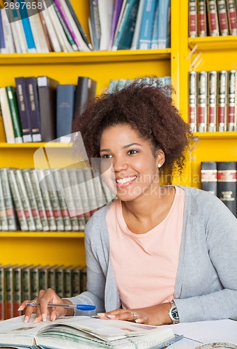 Image of Student With Books And Pen Looking Away In Library