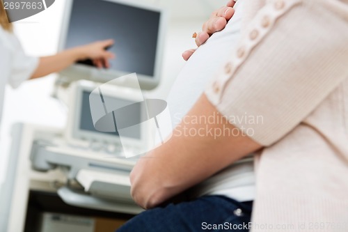 Image of Pregnant Woman With Doctor Pointing At Ultrasound Scan