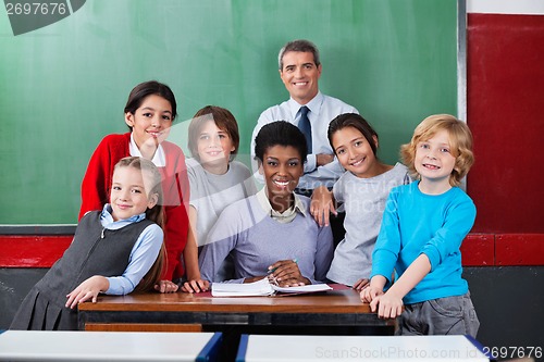 Image of Confident Teachers With Schoolchildren Together At Desk