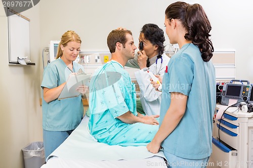 Image of Medical Team Examining Patient In Hospital