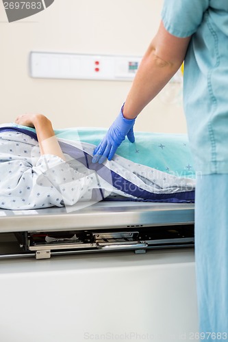 Image of Nurse Standing By Patient Lying On Xray Table