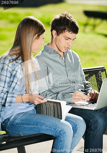 Image of Friends With Laptop And Book Sitting In Campus