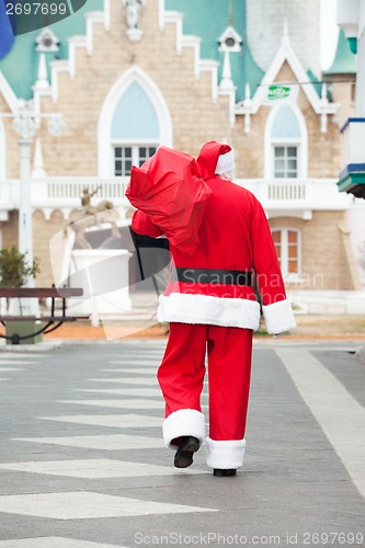 Image of Santa Claus Carrying Bag While Walking In Courtyard