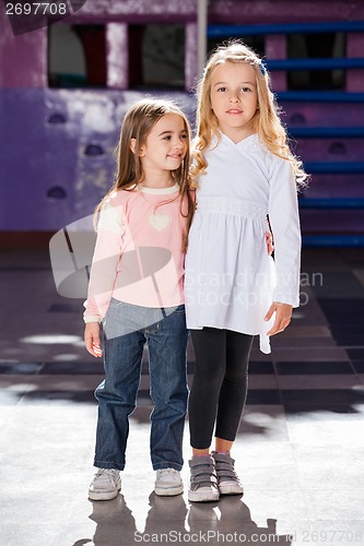 Image of Girl Standing Arms Around With Female Friend In Kindergarten