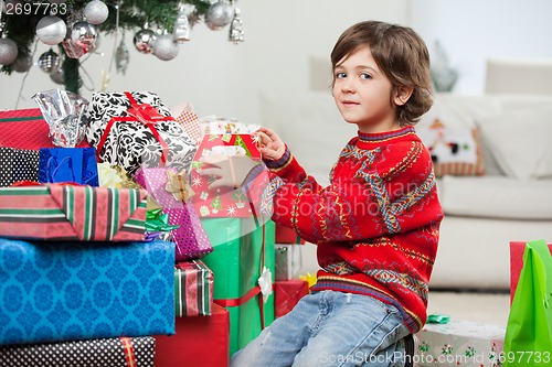 Image of Cute Boy Kneeling By Christmas Gifts