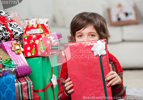 Image of Boy Holding Christmas Gift In Front Of Face