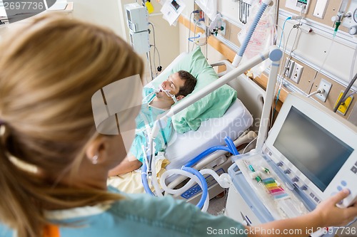 Image of Nurse Pressing Monitor's Button With Patient Lying On Bed